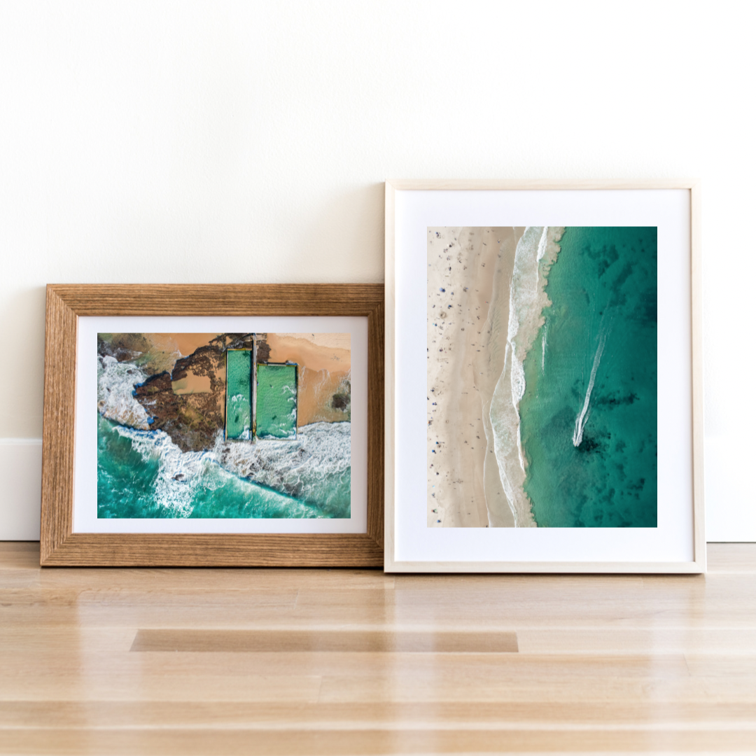 Two framed artworks on a wooden surface with a white wall background. Illawarra photography. Photo from Austinmer and Thirroul NSW