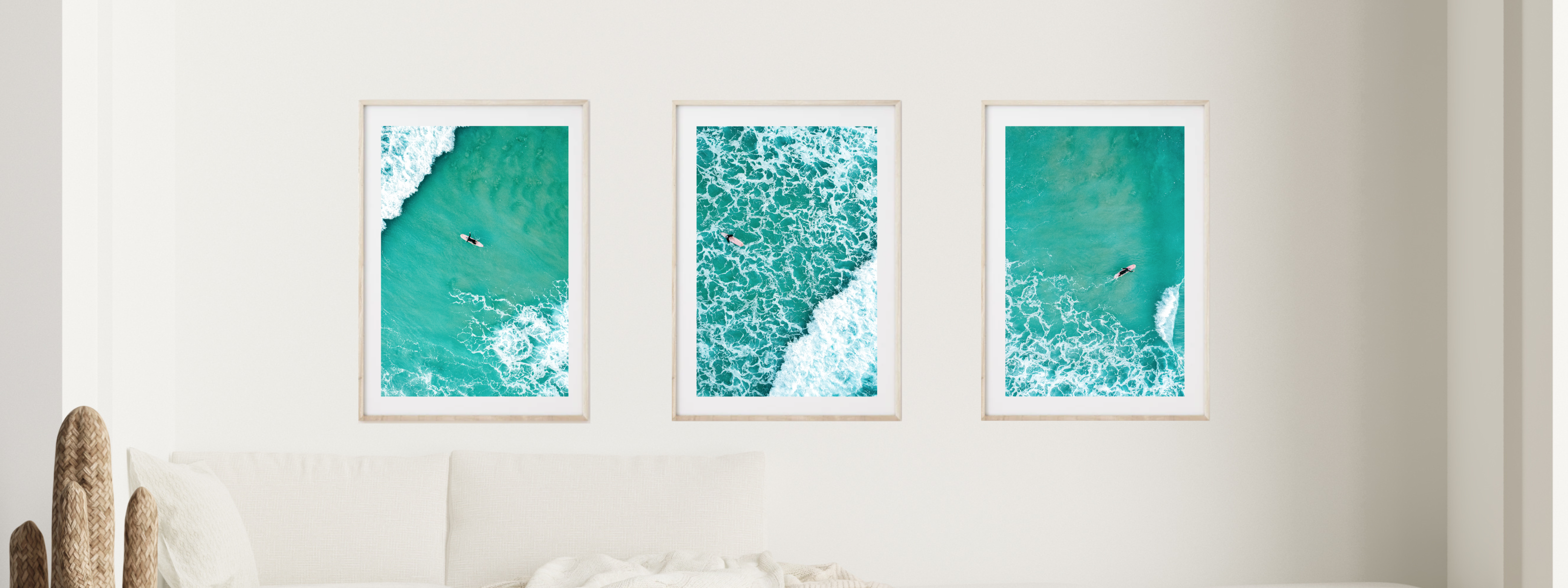 Three framed artworks of ocean scenes with surfers on a white wall. Illawarra Photography. Beautiful ocean wall art.